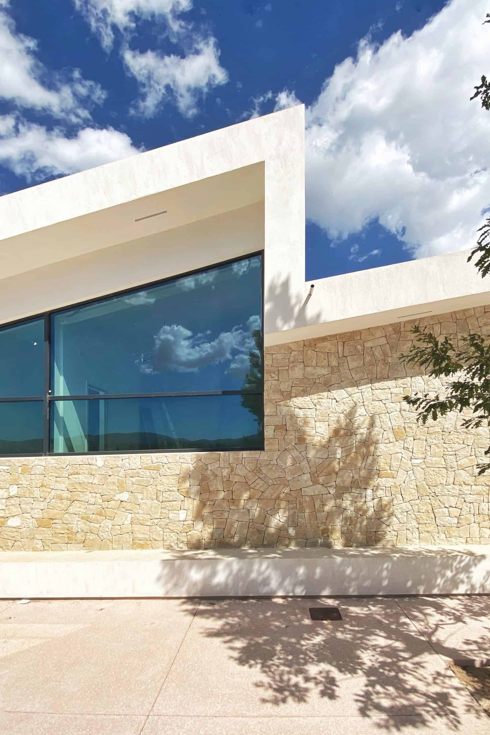 Vivienda contemporánea con fachada de piedra y grandes ventanales
